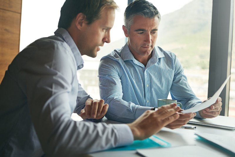 Two businessmen engaged in a discussion over paperwork in an office setting
