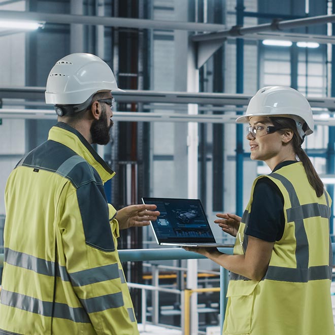 Two engineers in a robotics factory setting