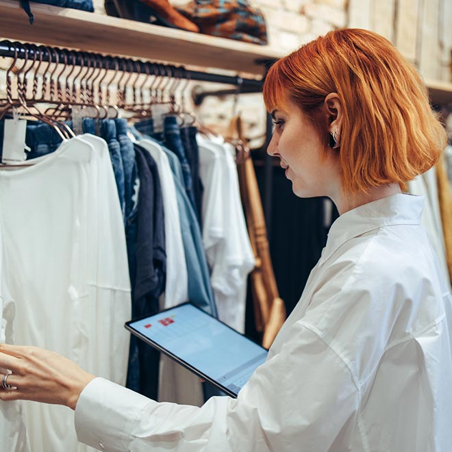 Woman taking inventory in a clothing store with a digital tablet